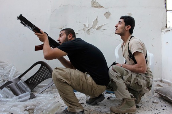 A Free Syrian Army fighter points his weapon as his fellow fighter watches in Aleppo's Al-Ezaa neighbourhood